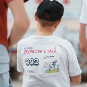 Chłopiec stojący tyłem w koszulce z napisem "Przygoda z tatą"