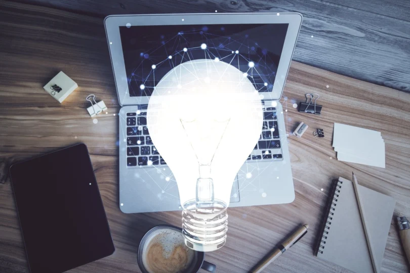 Zdjęcie przedstawia laptopa i żarówkę