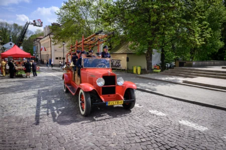 Strażacy podczas wydarzenia inaugurującego obchody jubileuszu 75-lecia powstania rzeszowskiej Komendy Wojewódzkiej PSP. Jadący zabytkowym wozem strażackim.