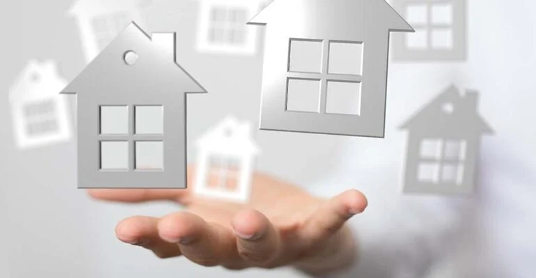 Grafika przedstawiająca zarys domków na otwartej dłoni.