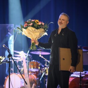 Paweł Steczkowski, uhonorowany prestiżowym Medalem Gloria Artis, z bukietem kwiatów.