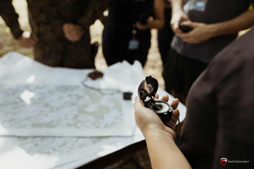 Zdjęcie przedstawia mapę osobę trzymająca w ręku kompas