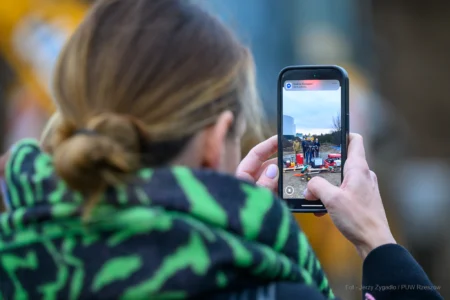 Dziennikarka robiąca zdjęcie komórką podczas konferencji prasowej.